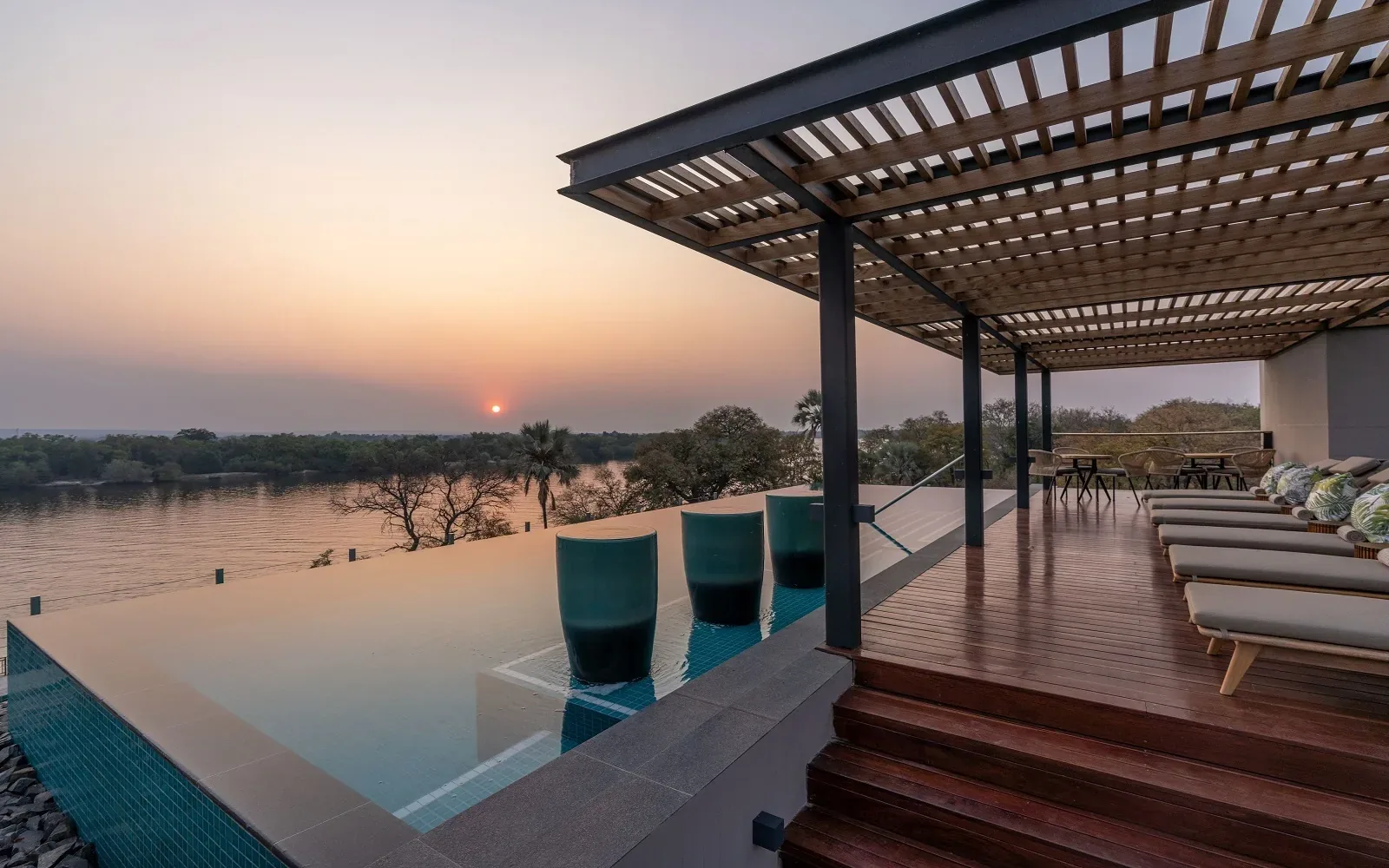 Infinity pool and shaded terrace overlooking the Zambezi River at sunset