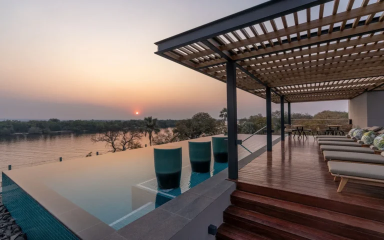 Infinity pool and shaded terrace overlooking the Zambezi River at sunset