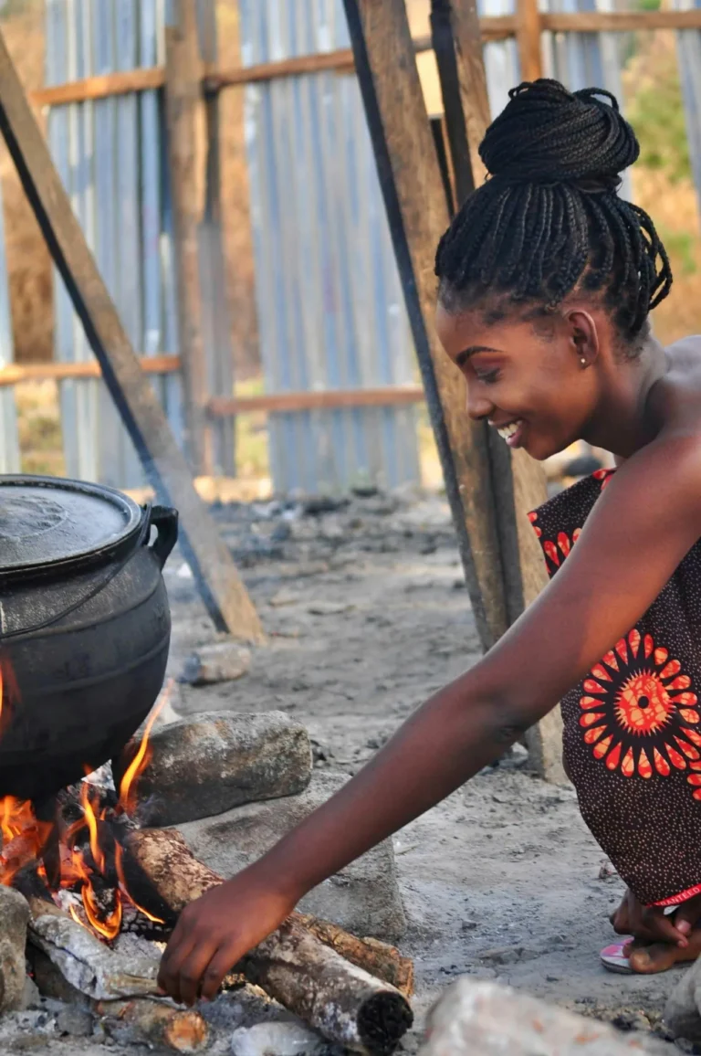 Woman tending a cooking pot over an open fire in Zambia